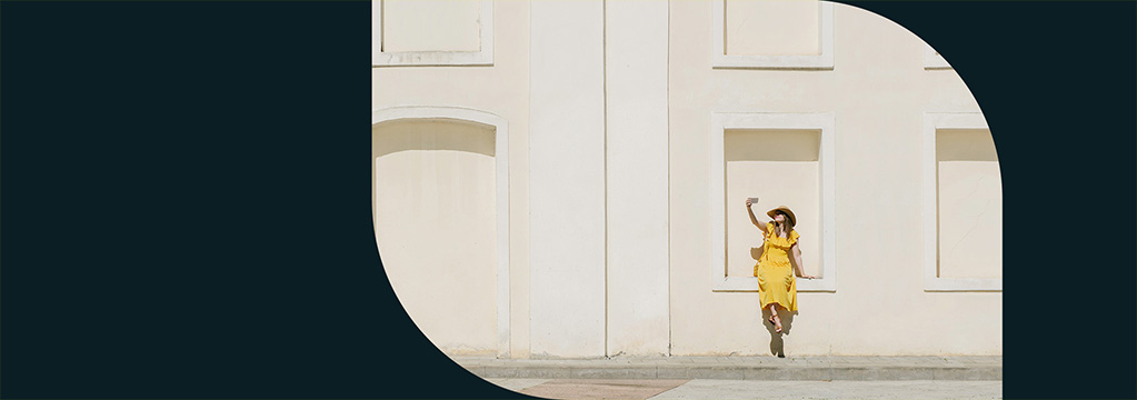 Eine Frau in einem gelben Kleid sitzt in einer Wandnische und macht ein Selfie. Sie freut sich &uuml;ber ihre Investition in Nachkaufanleihen.