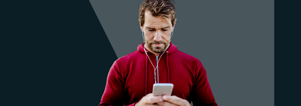 Ein Mann im roten Hoodie schaut konzentriert auf sein Smartphone.