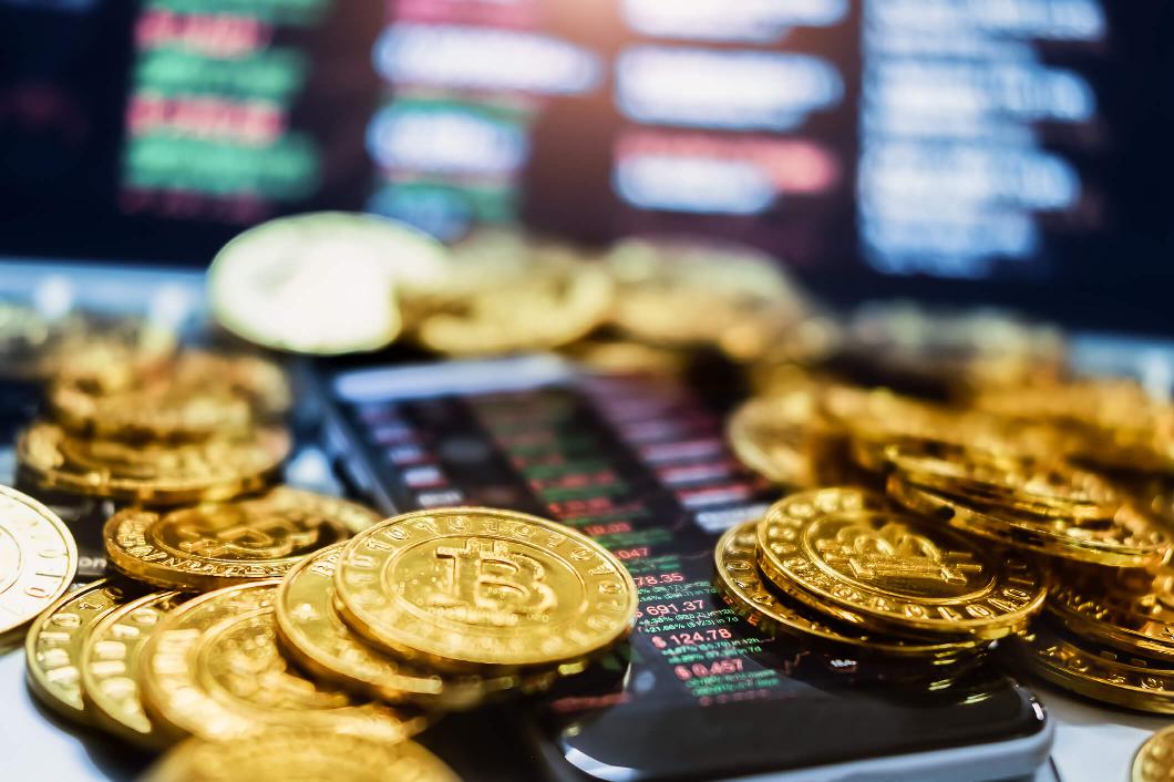 Bitcoin-Münzen liegen auf einem Smartphone.