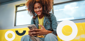 Eine junge Frau schaut gutgelaunt auf ihr Smartphone.