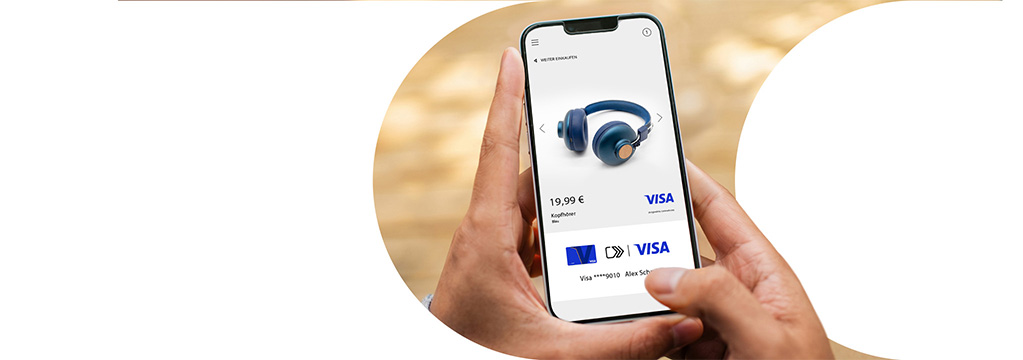 Eine Hand h&auml;lt ein Smartphone mit einer Shopping-App: Es sind Kopfh&ouml;rer f&uuml;r 19,99 Euro zu sehen, die Bezahlung mit Visa Click to Pay ist ausgew&auml;hlt.