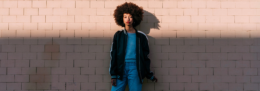 Frau lehnt entspannt an Wand im warmen Sonnenlicht