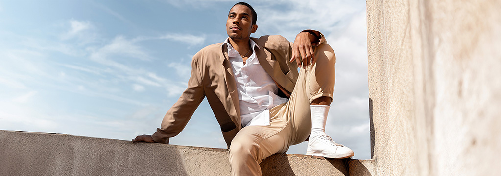 Mann sitzt gelassen auf einer Mauer in der Sonne