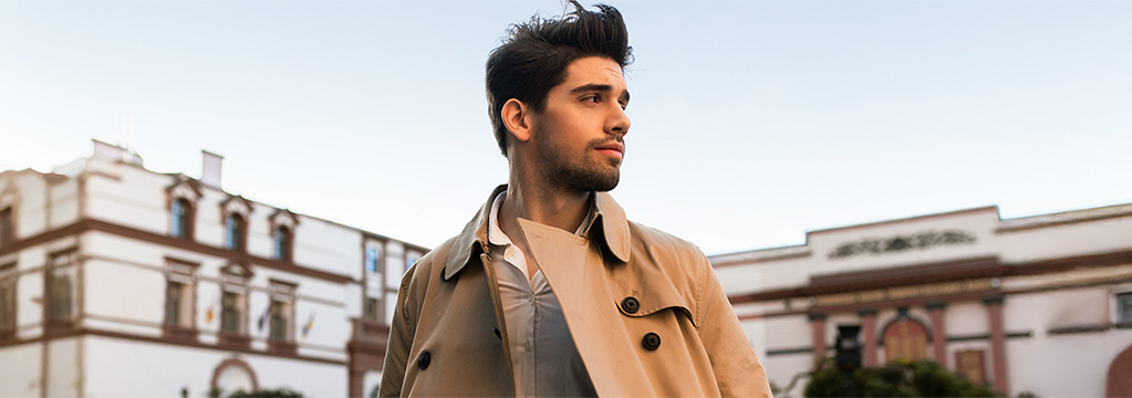 Nachdenklicher Mann im Mantel blickt durch die Stadt